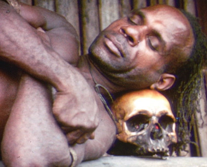 Asmat native sleeping on a skull.